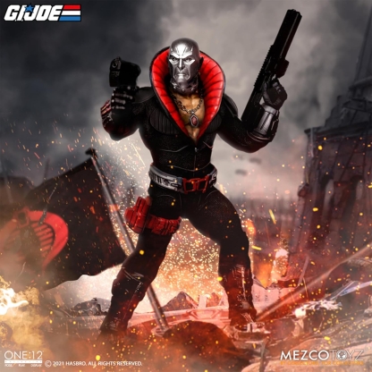 "Mezco One:12 Collective Destro action figure in a dynamic pose, holding a pistol in his left hand and a rifle in his right, standing amidst debris and fire with a COBRA flag in the background, in a battle-damaged cityscape."