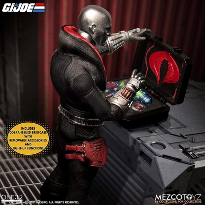 "Mezco One:12 Collective Destro action figure, viewed from the side, opening his Cobra-issued briefcase which displays a light-up function and removable accessories. A yellow bubble highlights 'INCLUDES COBRA-ISSUED BRIEFCASE WITH REMOVABLE ACCESSORIES AND LIGHT-UP FUNCTION!'."