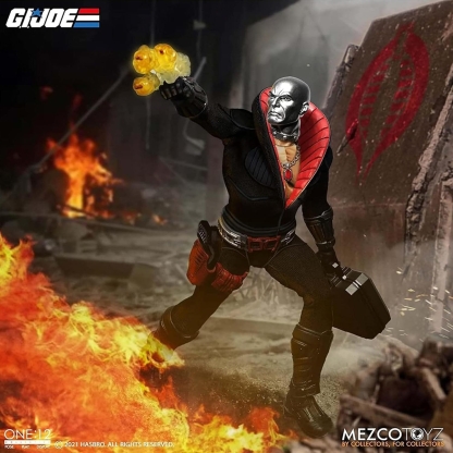 "Mezco One:12 Collective Destro action figure in an action pose, with a yellow blast effect attached to his outstretched hand, amidst fire and rubble, implying a battle scene."