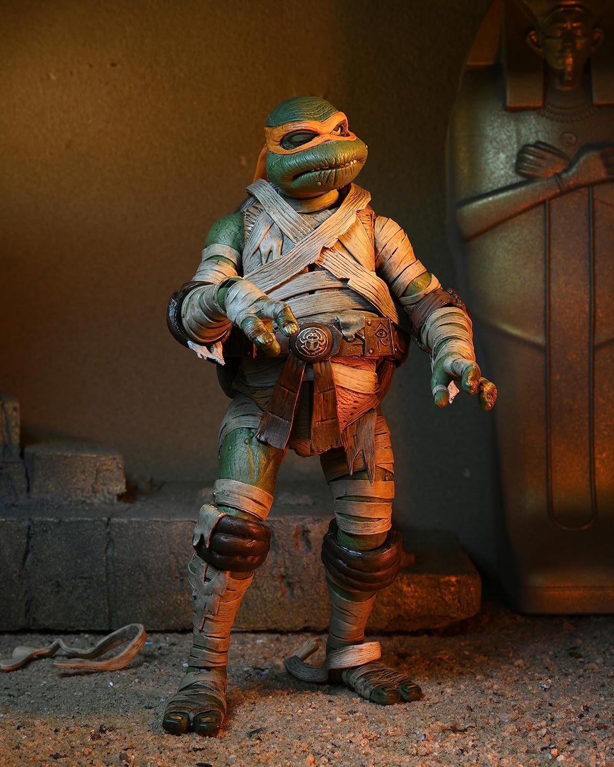 : A dynamic action pose of the NECA Michelangelo as The Mummy figure, demonstrating its range of articulation and weathered paint application.