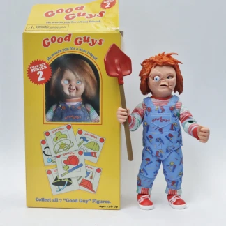 The Busted-Up Tommy action figure with a cracked face and red shovel standing next to its opened yellow Good Guy Blind Box Series 2 packaging.