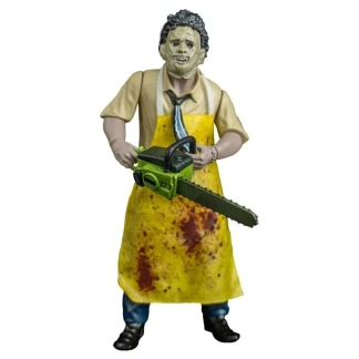 A 5-inch action figure of Leatherface wearing a yellow butcher's apron and stitched mask, holding a chainsaw inside retro blister pack packaging.